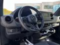 Interior view of a 2022 Mercedes-Benz Sprinter featuring a steering wheel dashboard and control panel with multimedia screen and cup holders