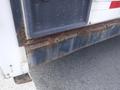 A close-up view of the lower rear section of a 2010 Forest River Enclosed trailer showing visible rust and deterioration on the metal surface