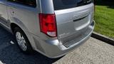 A silver 2016 Dodge Grand Caravan parked with its rear visible showing the taillights and the model name on the back