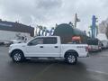 A 2017 Ford F-150 in white with a large cargo bed and orange equipment in the back, parked with its profile facing the viewer