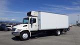 A white 2009 Hino 268 box truck with a refrigeration unit on top and five spoke wheels parked in a lot