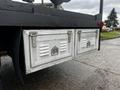 A silver metal storage box with slatted vents mounted on the back of a Freightliner M2 106 truck