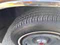 Close-up of the tire of a 1982 Mercury Grand Marquis showing a tread pattern and chrome wheel rim with a red emblem in the center