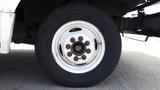 A white wheel of a 2011 Ford Econoline with visible rust on the lug nuts and a black tire