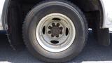 Close-up of a tire and wheel from a 2011 Ford Econoline with visible wear and dirt on the surface and a six-bolt pattern on a white rim