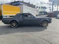 A vintage 1966 Ford Mustang with a sleek design and black body features gold wheels and a side profile view showcasing its classic silhouette