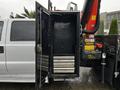 A 2014 Ford F-550 with an open black tool storage cabinet featuring several metal drawers inside