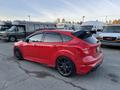 A red 2018 Ford Focus with black rims and a rear spoiler parked in a lot