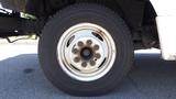 Close-up of a white wheel from a 2011 Ford Econoline with a steel rim and eight lug nut holes visible on the tire