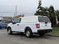 A white 2018 Ford F-150 pickup truck with a covered bed parked on a street