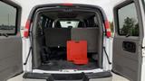 The rear interior of a 2017 Chevrolet Express Quigley 4x4 van featuring a gray upholstery and a red metal accessory placed on the floor