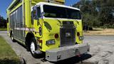 A bright yellow 1995 Freightliner FLL086 with a silver grille and shiny chrome front bumper is parked with its door open