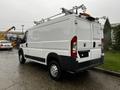 A white 2018 RAM Promaster van with a high roof and ladder rack on the roof viewed from the rear angle