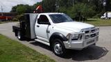 A white 2014 RAM 5500 truck with a flatbed and equipment rack positioned at the front. The vehicle features chrome grille and running boards