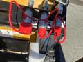 Close-up of three red valve caps on a mini skid steer with metallic fittings and labeled instructions attached