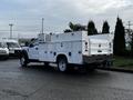 A white 2017 Ford F-550 with a utility bed equipped with storage compartments and a mounted air conditioning unit on the back