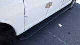 A white 2015 GMC Savana with a black step rail along the side and a silver door handle