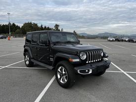 A black 2019 Jeep Wrangler with a distinctive front grille and rugged design parked in a lot