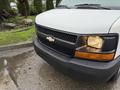 A white 2009 Chevrolet Express van with a black grille and orange headlights located in a wet area