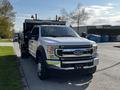 A 2021 Ford F-550 truck in front view with a shiny silver exterior and a black flatbed attachment fitted with lights on top