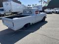 A light gray 1962 Ford F-100 pickup truck with a sleek body design and black wheels parked in a lot