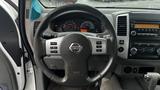 Steering wheel and dashboard of a 2016 Nissan Frontier featuring gauges and a radio with various buttons and controls