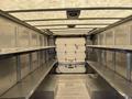 Interior of a 2011 Ford Econoline van featuring metal shelves on both sides with a roll-up door at the back