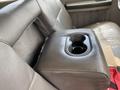 A leather-covered center console with a cup holder in the rear seat of a 2010 Ford F-550