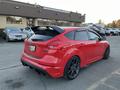 A red 2018 Ford Focus with a sporty design featuring a rear spoiler and black alloy wheels parked in a lot