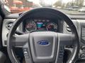 A close-up view of the steering wheel and dashboard of a 2014 Ford F-150 displaying various gauges and controls