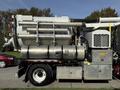 A side view of a 2013 International 7400 truck equipped with a large vacuum tank and several suction tubes connected to the top