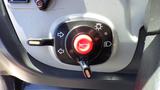 A round control knob with a red center and black outline featuring icons for lights and warning indicators