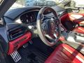 Interior of a 2023 Acura MDX featuring a black and red color scheme with a steering wheel gear shifter and dashboard display