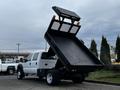 A 2015 Ford F-550 dump truck with an open bed tilted upwards displaying its dumping mechanism