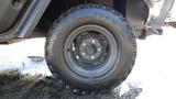 Close-up of a black tire belonging to a 2013 Kubota RTV 1100 showcasing its rugged tread design