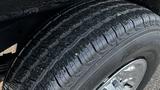 A close-up of a tire from a 2005 Chevrolet Express showcasing its tread pattern and water droplets on the surface