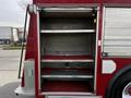Interior compartments of a red 1994 Freightliner FL80 fire truck with three shelves for storage