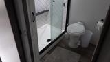 A bathroom featuring a shower stall with glass doors a toilet and a small rug on the floor