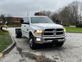 A 2018 RAM 3500 pickup truck with a bright white exterior and chrome front grille parked on a street with a flatbed design and no cargo attached