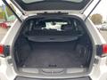 A 2018 Jeep Grand Cherokee with an open trunk showcasing a spacious cargo area and foldable seats