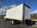 A 2013 International 4300 box truck with a white cargo area and black wheels parked on a gravel surface