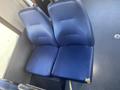 Two blue fabric seats are positioned closely together with a small tear on the right seat cushion