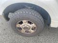 A close-up of a 2009 Ford F-150 tire with a rugged tread pattern showing dirt and wear