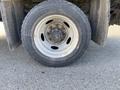 A close-up of a wheel from a 2003 Ford F-450 SD featuring a silver rim and a black tire with visible tread and wear marks