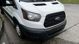 A white 2017 Ford Transit van with a black grille and prominent headlights parked on a street