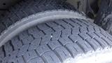 Close-up of two tires on a 2011 Ford Econoline showing tread pattern and a small nail embedded in one tire