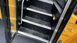 Inside view of the entry stairs of a 2014 Freightliner Thomas Bus Diesel showing four metal-treaded steps with a handrail