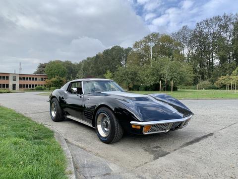 A black 1972 Chevrolet Corvette with a sleek design and distinctive curves is parked with the sun reflecting off its glossy exterior