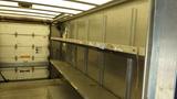 Interior view of a 2011 Ford Econoline cargo van with metal shelving along the sides and an empty floor space