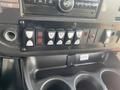 Dashboard controls of a 2018 Chevrolet Express featuring various buttons for lights and features with a cup holder below